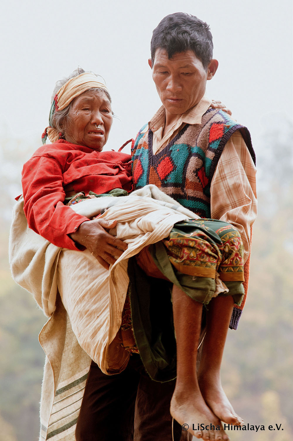 Ein Mann trägt kranke Frau zu LiScha Himalaya e.V.